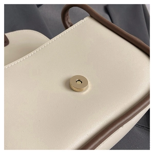 Macro detail of creamy white faux leather surface and golden round magnetic buckle closure