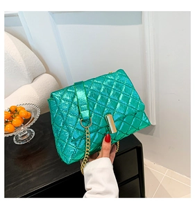 Detail of metallic green quilted crossbody bag with gold chain strap and turn-lock closure