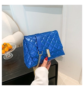 Detail of blue quilted leather bag with metallic finish and gold rectangular clasp