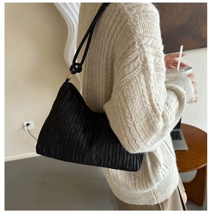 Détail du sac à bandoulière plissé noir avec anneau doré et fine bandoulière
