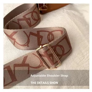 Detail of adjustable wide woven shoulder strap with geometric pattern and gold buckle