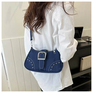 Detail of dark blue denim shoulder bag with silver buckle and metal rivet accents