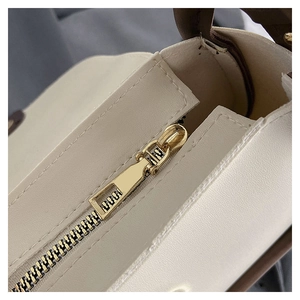 Detailed close-up of golden metal zipper and beige PU leather texture on a chic handbag