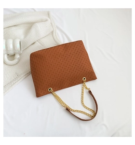 Primer plano del bolso tote marrón con textura tejida y cadena dorada sobre tela
