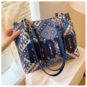 Detail of bohemian geometric woven tote bag with chain strap and blue applique patch