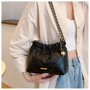 Detail of black quilted leather bucket bag with gold chain strap and metal ball charm
