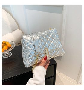 Detail of silver quilted chain bag with metallic texture and gold clasp buckle
