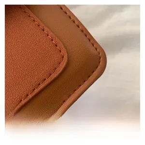 Close-up of caramel leather texture and precise double stitching on the crossbody bag