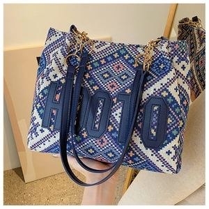 Close-up of geometric woven tote bag featuring H0010 leather patch and chain strap