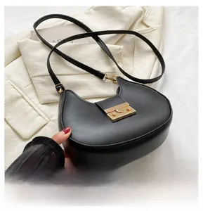 Close-up of black leather half-moon saddle bag featuring a large gold metallic square lock