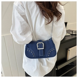 Detail of dark blue denim shoulder bag with silver chain and rivet accents