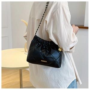 Detail of black quilted leather shoulder bag with gold metal hardware and chain strap