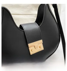 Close-up of golden square buckle on black leather crescent bag with refined hardware detail