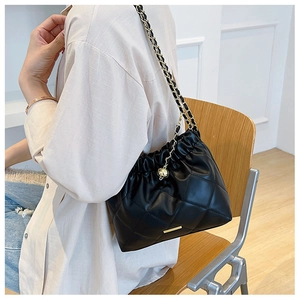 Detail of black quilted leather shoulder bag with metal chain strap and logo plaque