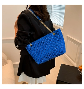 Détail d'un grand cabas matelassé bleu avec chaîne dorée porté par un mannequin
