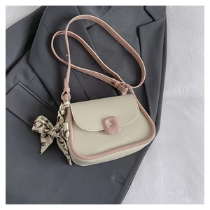 Detail view of mini flap crossbody bag with pink trim and decorative silk scarf accessory