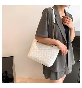 Detalle de bolso tote tejido blanco con elegante correa de hombro de cadena dorada