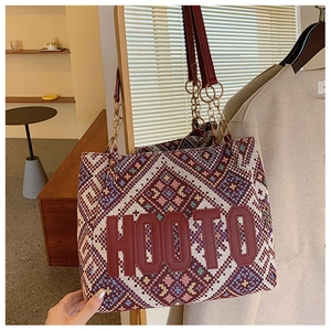 Detail of bohemian woven tote bag featuring geometric patterns and red letter patch design