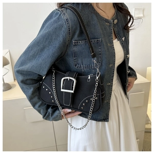 Close-up of black denim shoulder bag featuring silver metal buckle and punk rivet details