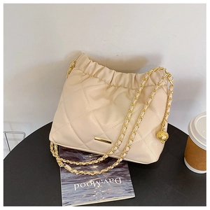 Detail of cream quilted shoulder bag with gold chain strap and drawstring cloud design