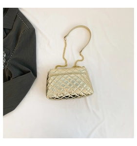 Macro view of metallic gold quilted handbag with elegant chain strap and leather detail