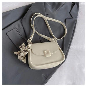 Detail of cream saddle bag with a decorative silk scarf on a grey blazer background