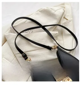 Detailed close-up of adjustable strap and golden metal buckle on black crescent bag