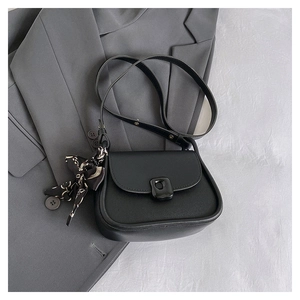 Detail of black semi-circular crossbody bag with decorative scarf on grey blazer background