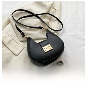 Macro view of compact black hobo bag with gold buckle next to a mobile phone