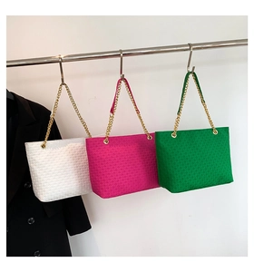 Detalle de bolsos shopper trenzados en blanco, rosa y verde con correas de cadena dorada