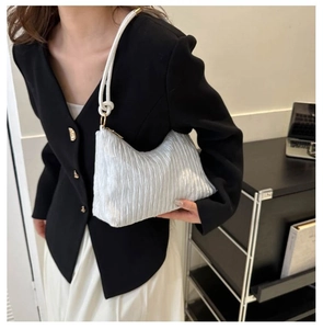 Détail du sac sous les bras en tissu plissé argenté avec une anse en corde tressée
