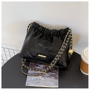 Detail of black quilted leather shoulder bag with gold chain and drawstring closure