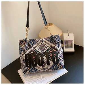 Detail of colorful geometric woven tote bag featuring black HOOTO leather letter appliqué