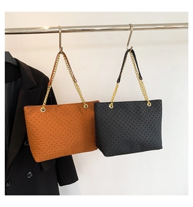 Detalle de bolsos tote tejidos en negro y marrón con correas de cadena de metal dorado
