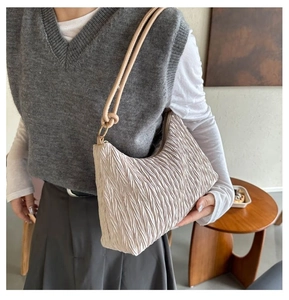 Détail du sac cabas plissé blanc cassé montrant la texture accordéon et la bandoulière nouée