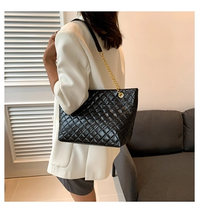 Détail du grand sac cabas noir matelassé avec bandoulière chaîne dorée et cuir brillant