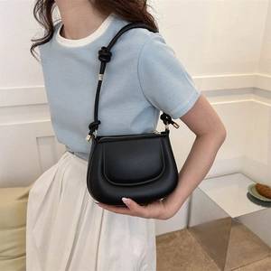 Sac à bandoulière minimaliste en cuir noir mat avec finitions dorées et nœud décoratif
