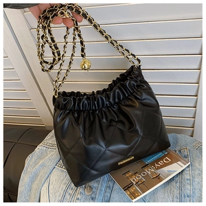 Detail of black quilted leather crossbody bag with golden chain and adjustable metal ball