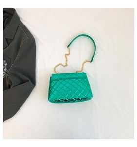 Top-down view of bright green quilted leather handbag with gold chain strap on white fabric