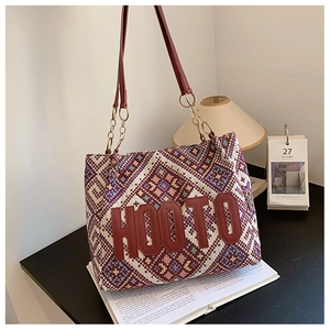 Detailed shot of ethnic woven tote bag with HOOTO logo on a vintage book setting