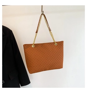 Detalle del bolso tote trenzado caramelo con elegante correa de cadena de metal dorado