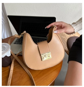 Top view of light brown crescent shoulder bag with gold buckle on an office desk