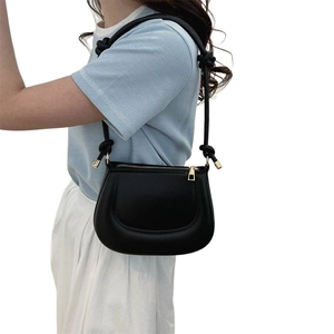 Sac hobo noir minimaliste avec détail de nœud sur la bandoulière et zip doré brillant