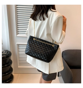 Détail du sac bandoulière matelassé noir avec chaîne dorée porté par un mannequin de profil
