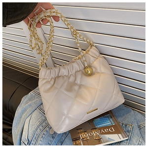 Detailed view of beige quilted cloud bag with gold chain strap and metal plate decor