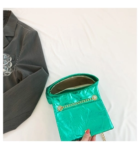 Close-up of metallic green quilted crossbody bag with gold chain and beige interior