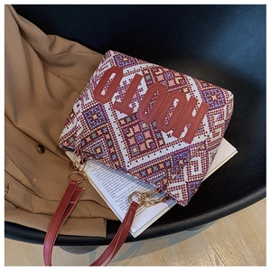 Close-up of ethnic woven tote bag with red leather straps and golden metal chain detail