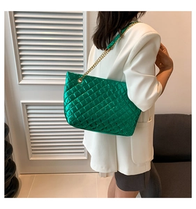 Détail du sac cabas vert matelassé brillant avec bandoulière en chaîne dorée à l'épaule