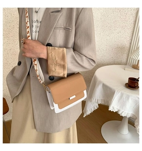 Detail of a brown and white square bag with a wide jacquard strap and silver metal lock