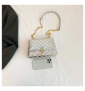 Close-up of silver quilted crossbody bag with gold chain strap and metal lock detail